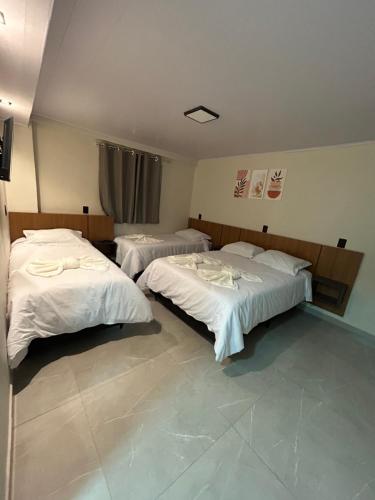 a room with two beds with white sheets at Castilhos Hotel in Barracão