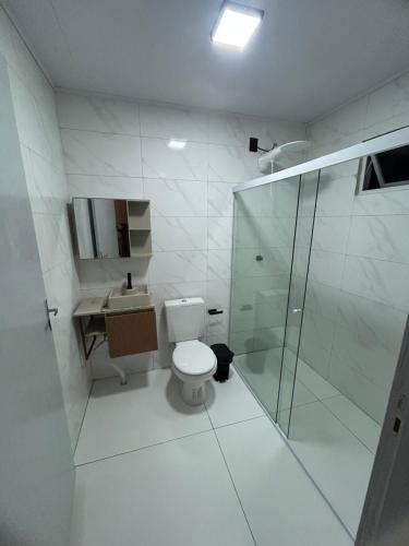 a white bathroom with a toilet and a shower at Castilhos Hotel in Barracão