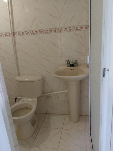 a white bathroom with a toilet and a sink at Casa Finca pasadia cerete in Cereté