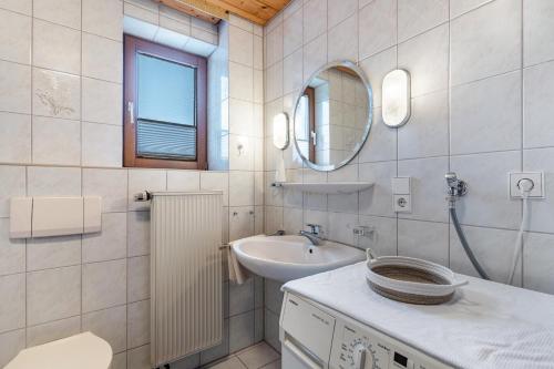a white bathroom with a sink and a mirror at Fewo Schwarzwald - Haus Sommerberg in Baiersbronn