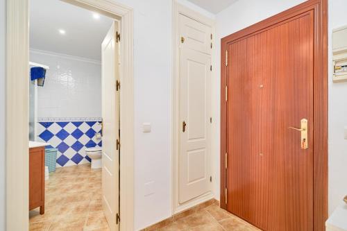 a bathroom with a toilet and a wooden door at Apto Urb Centro Internacional A117 in Torrox