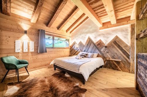 a bedroom with a bed and a green chair at Le Perray Alpine Lodge in Abondance