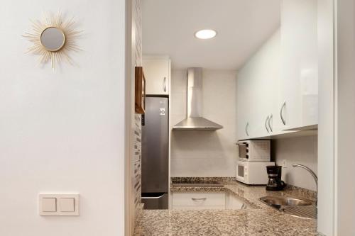 a kitchen with white cabinets and a stainless steel refrigerator at Playamarinsa in Torre del Mar