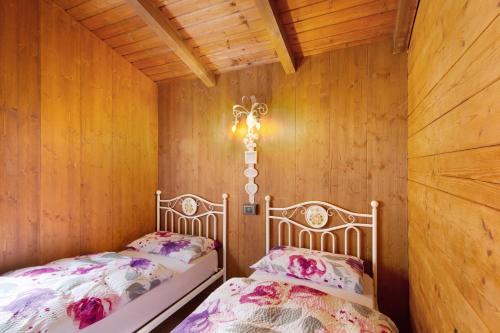 two beds in a room with wooden walls at Orserose Chalet 3 I Ciodi in Forno di Zoldo
