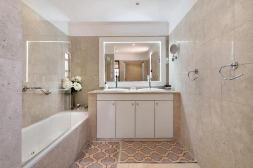 a bathroom with two sinks and a tub and a mirror at V4 Galeão Vilamoura in Vilamoura