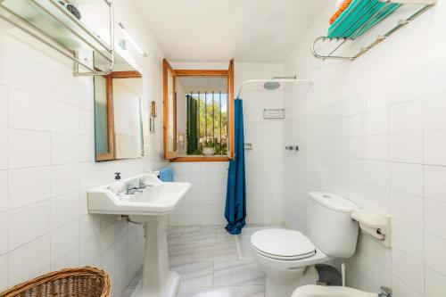 a white bathroom with a toilet and a sink at Finca Ses Coves in Petra