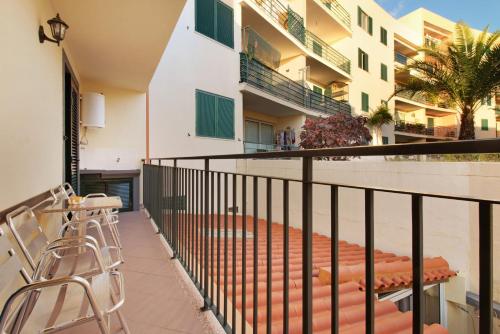 a balcony with a table and chairs and a building at Palheiro Residence Familiar 1 in Funchal