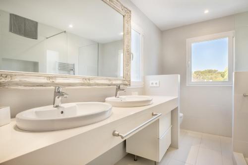 a white bathroom with two sinks and a mirror at Villa Es Cantò in Cacla D'or