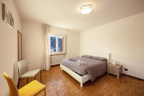 a bedroom with a bed and a chair and a window at Appartamento Cornon in Tesero