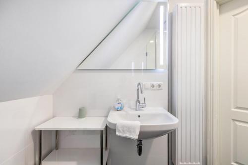 a white bathroom with a sink and a staircase at Villa Elysium in Heide
