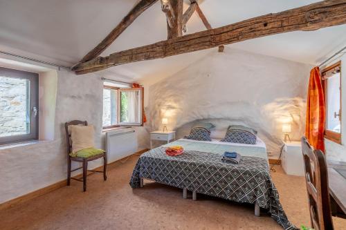 a bedroom with a bed and a chair in a room at Maison dans Village médiéval in Olargues