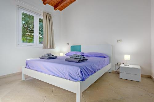 a white bedroom with a large bed with purple sheets at Stazzu Gallurese in Olbia
