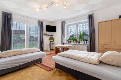 a bedroom with two beds and a table and windows at Ferienwohnung Am Brunnen in Durbach