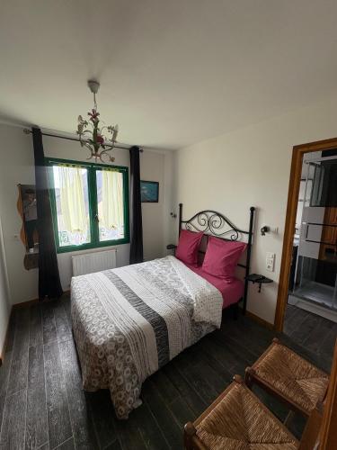 a bedroom with a bed with pink pillows and a window at Chambres D'hôtes Mongarny Cancale in Cancale
