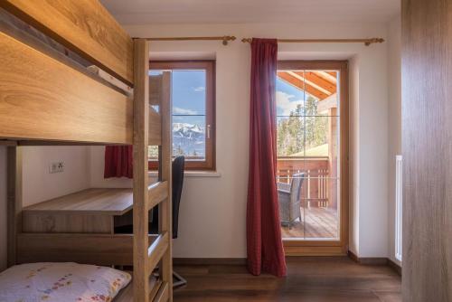 a bedroom with bunk beds and a balcony with a window at Golserhof Sonne in Cadipietra