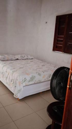 a bedroom with a bed and a fan and a chair at Casa da Mari in Caucaia