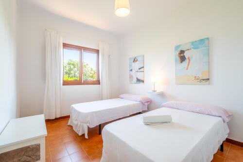 zwei Betten in einem weißen Zimmer mit Fenster in der Unterkunft Es Viola in Santa Eugènia