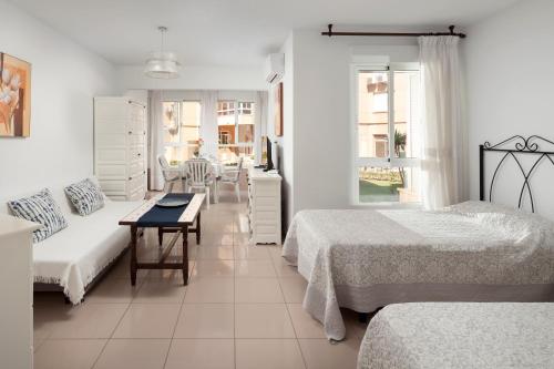 a white bedroom with two beds and a table at Estudio Bloque 90 in Torrox