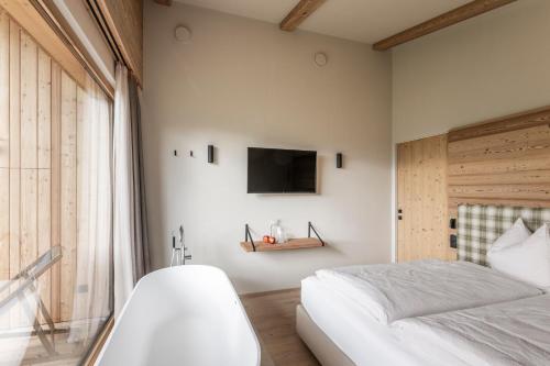 a bedroom with a bed and a tv on the wall at Oberplunerhof Luxury Chalet Woods in Chienes