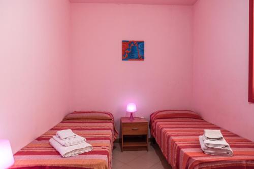 two twin beds in a room with a pink wall at Appartamento D - Le Terrazze in Ribera