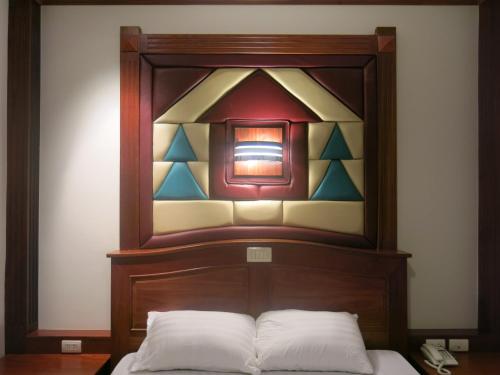 a bedroom with a wooden headboard with a stained glass window at SP Park Cha-am in Cha Am