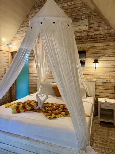 a bedroom with a bed with white drapes at Danys House at Tiki Bar and More in Nusa Lembongan