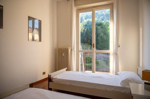 two beds in a room with a large window at Verbania Panorama Lago in Verbania