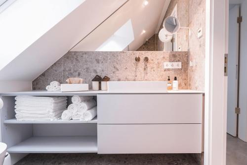 a bathroom under the stairs with white shelves and towels at 4 Personen Apartment 47 in Überlingen