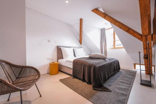 a white bedroom with a bed and a chair at 4 Personen Apartment 47 in Überlingen