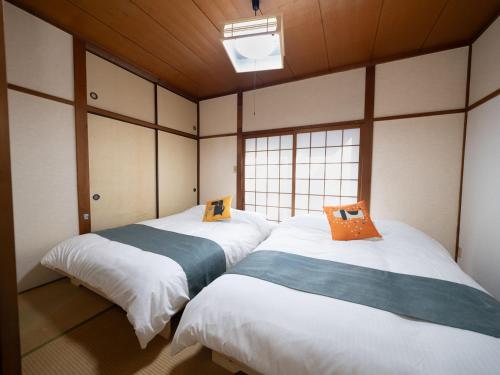 two beds in a room with a window at 小豆島宿いたち in Tonosho