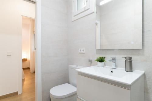 a white bathroom with a toilet and a sink at Apartamento Calderon in Barbate