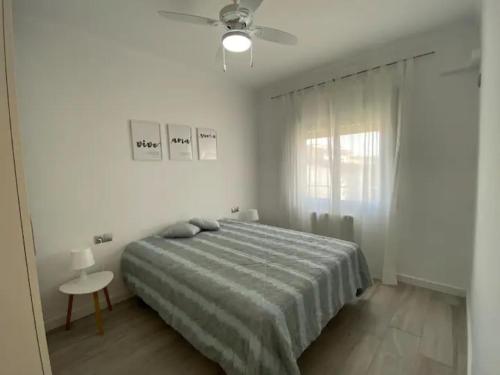 a white bedroom with a bed and a ceiling fan at Montiro in L'Escala
