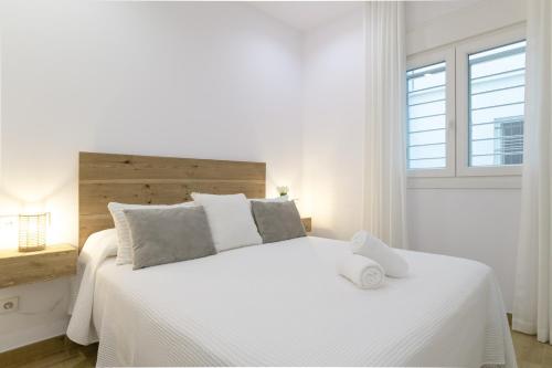 a white bedroom with a large white bed with a window at Apartamento Calderon in Barbate