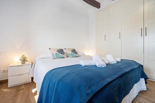 a white bedroom with a large bed with blue blanket at Loft Jb in L'Ametlla de Mar