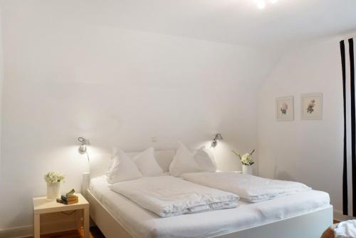 a white bed with white sheets and pillows at Ferienhaus Neudorf in Varel