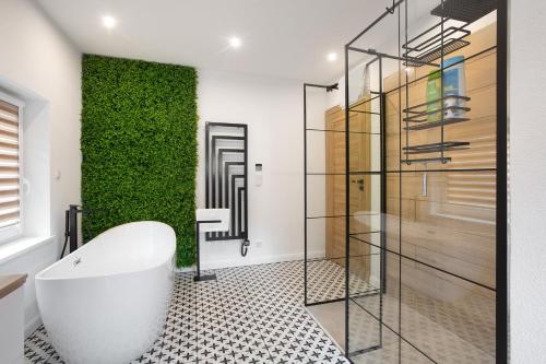 a bathroom with a white tub and a green wall at Heimelige Schwarzwaldwohnug Berg in Häusern