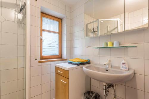 a white bathroom with a sink and a window at Ferienwohnung Chiemgau - erleben in Siegsdorf