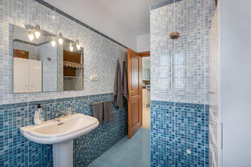 a blue tiled bathroom with a sink and a mirror at La Casa de Maika in Guatiza