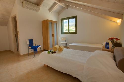 a bedroom with a large white bed and a window at Villa Mataki Ideales Resort in Kefallonia