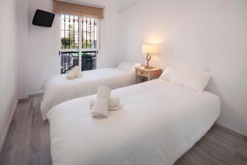 two white beds in a room with a window at Experiencia Marina A107 in Torrox