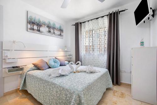 a bedroom with a bed with a television and a window at Sol y Mar Caleta de Fuste in Caleta De Fuste