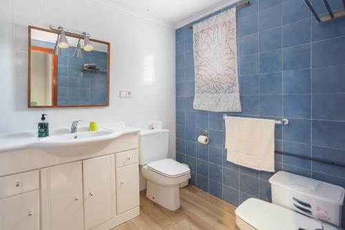 a blue tiled bathroom with a toilet and a sink at Adosado Mareny Blau in Mareny Blau