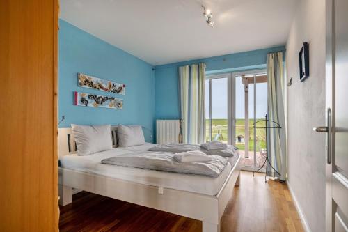 a bedroom with a bed with a blue wall at Haushälfte Süderhafen in Nordstrand