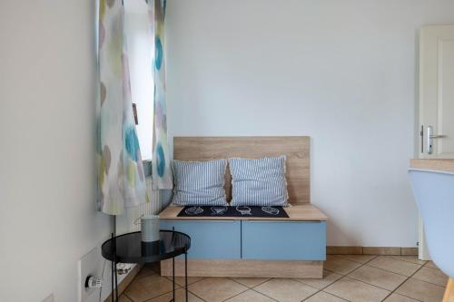 a room with a bench with two pillows and a table at Haushälfte Süderhafen in Nordstrand