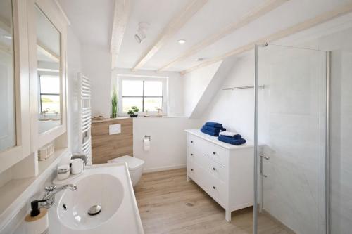 a white bathroom with a sink and a toilet at Ferienhaus 'Huus ant Diek mit Pool' in Norden