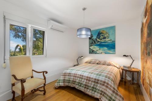 a bedroom with a bed and a chair and windows at Finca El Dragonal With Private Pool in Santa Brígida