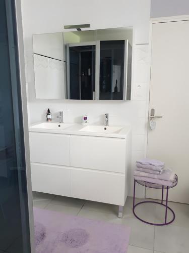 a bathroom with two sinks and a mirror and a stool at Chambre Chanteloup in Mont-Dol