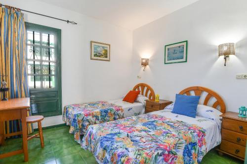 a bedroom with two beds and a desk and a window at Mimosa B1 in Puerto del Carmen