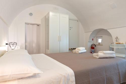 a white bedroom with a large bed with towels on it at Suite Le Cementine in Mottola