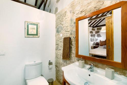 a bathroom with a sink and a toilet and a mirror at La casa nueva in Fátaga